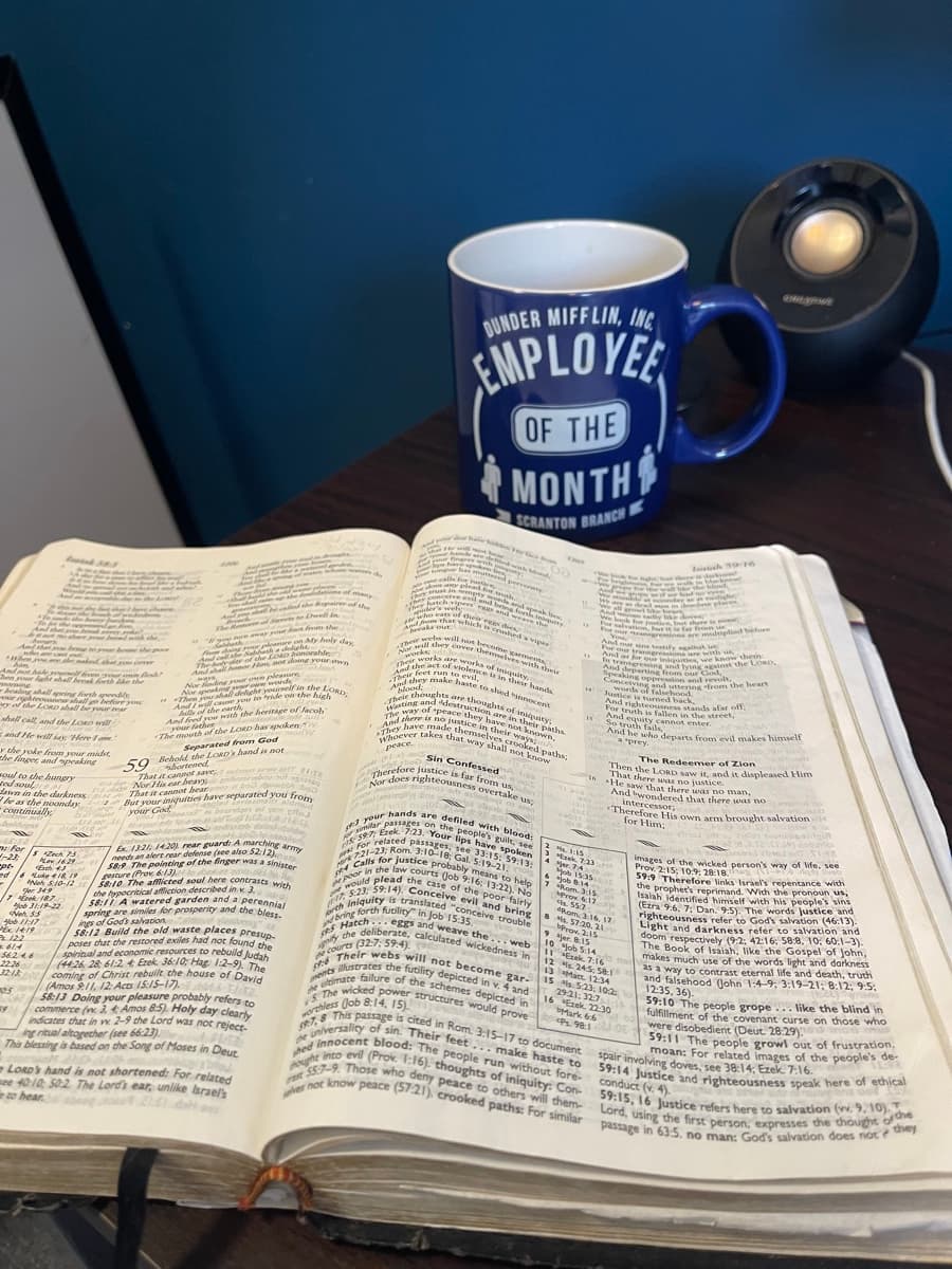 An open Bible on a table next to a coffee mug, well-worn and marked up from daily use