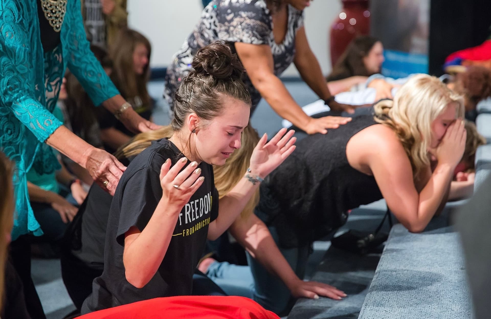 Woman in prayer wearing a Freedom From Addiction shirt