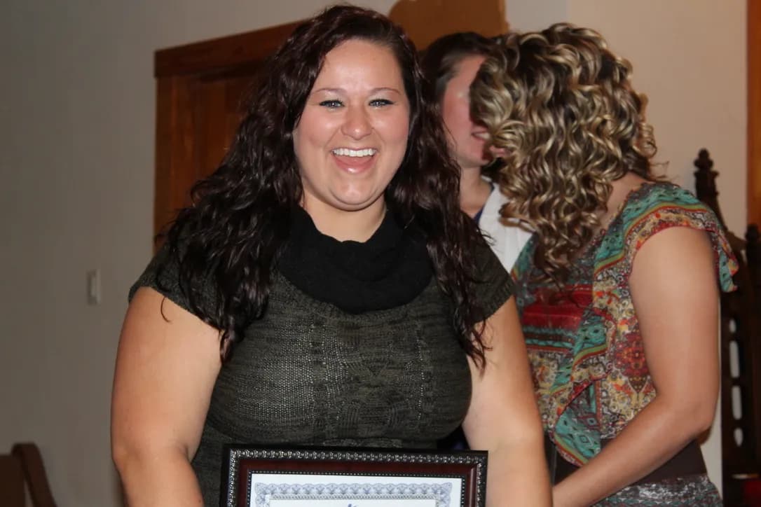 A Teen Challenge graduate smiling while holding her framed graduation certificate