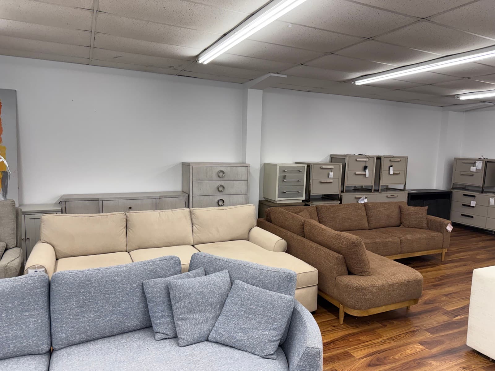 Blue, cream, and brown sectionals with dressers along the wall