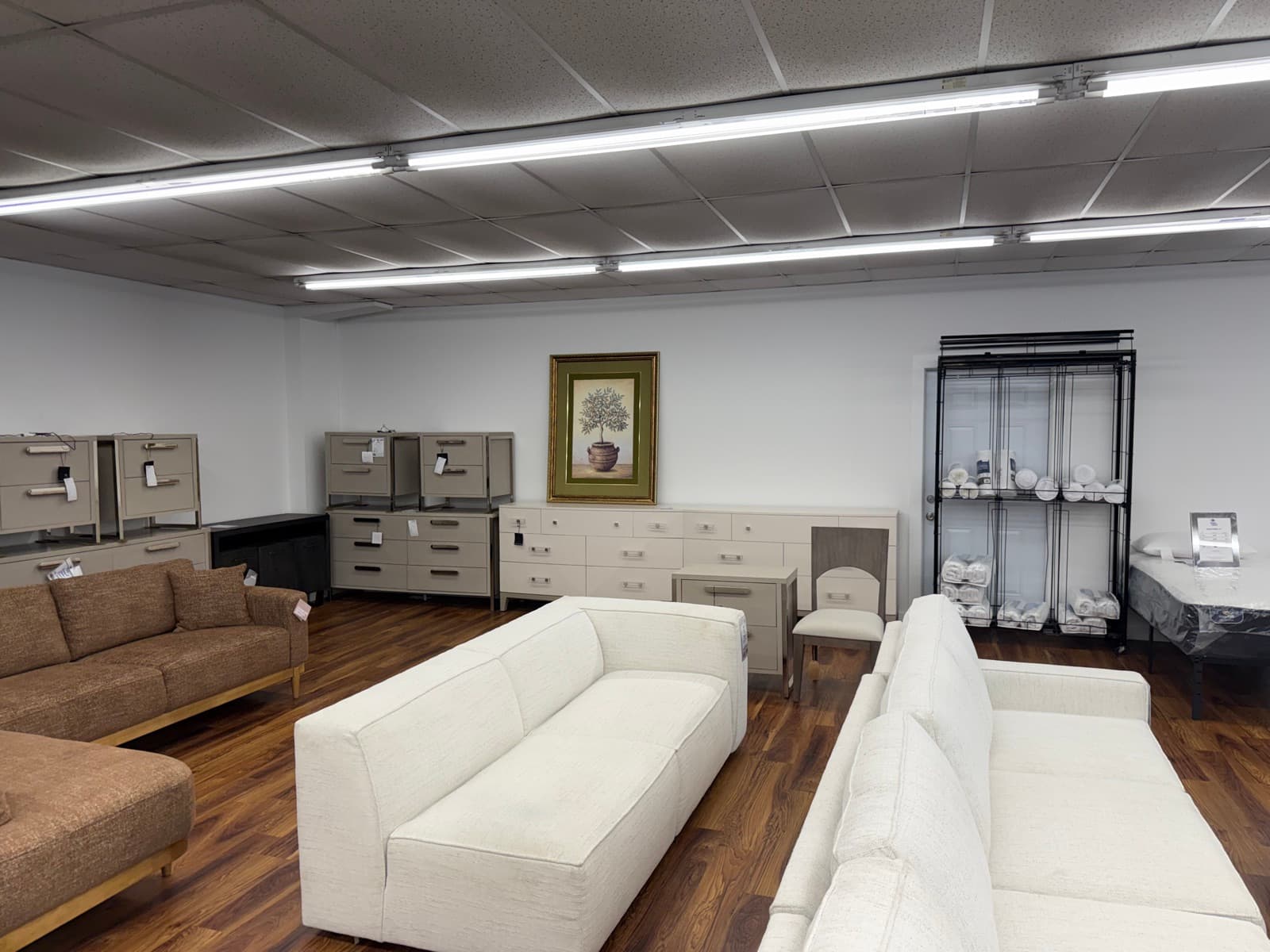 White sofas with dressers and bedding along the back wall