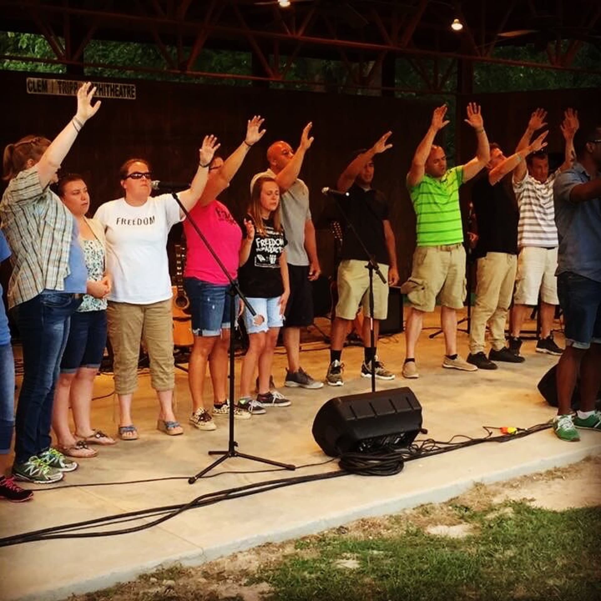 Open-air worship gathering at an outdoor amphitheater under a wide sky