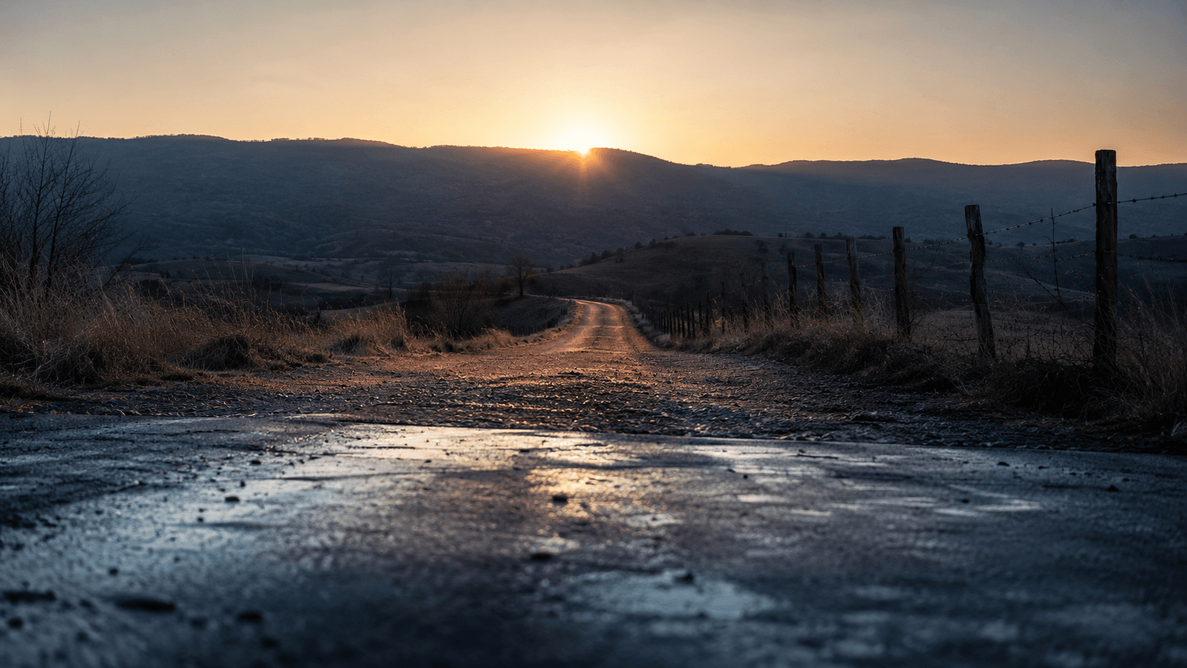 Gravel road at dawn leading toward a Virginia ridgeline, cold shadow behind and warm amber light ahead.