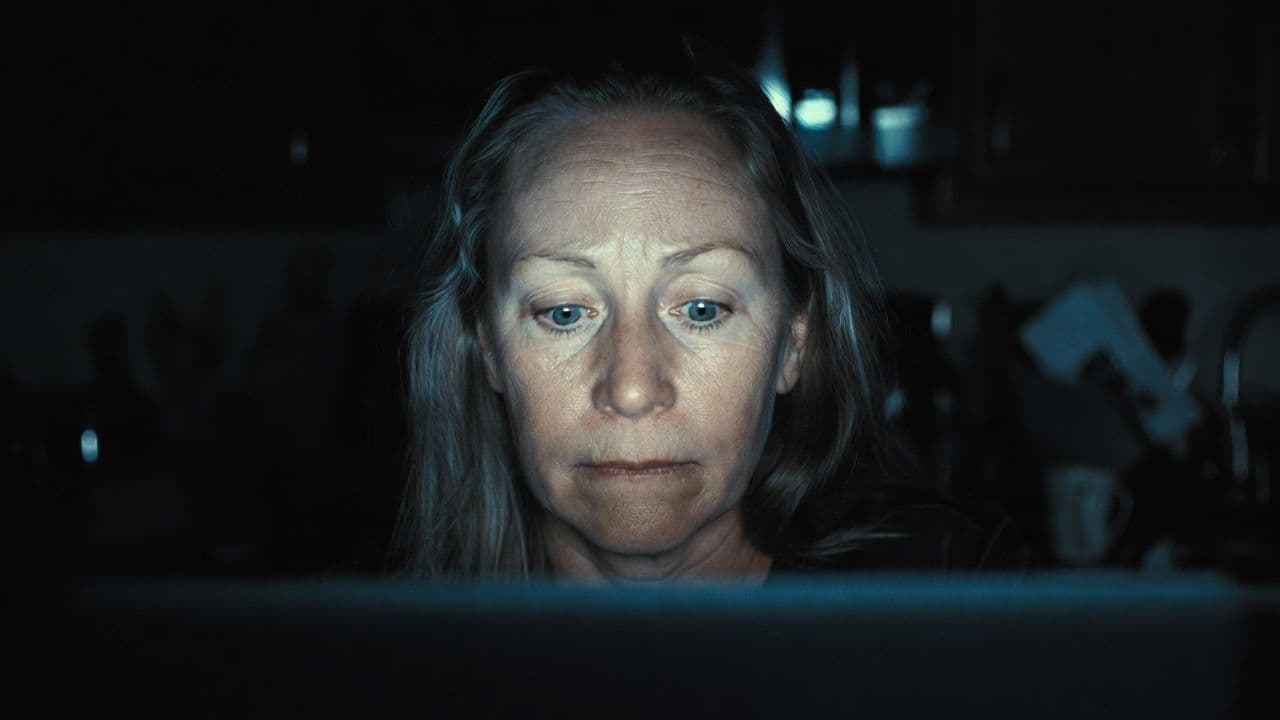 A worried middle-aged mom searches late at night on her laptop in a cozy home office, looking for faith-based recovery program options with hope and determination