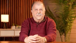 Portrait of Rev. John Franich seated at a table in a warm studio setting