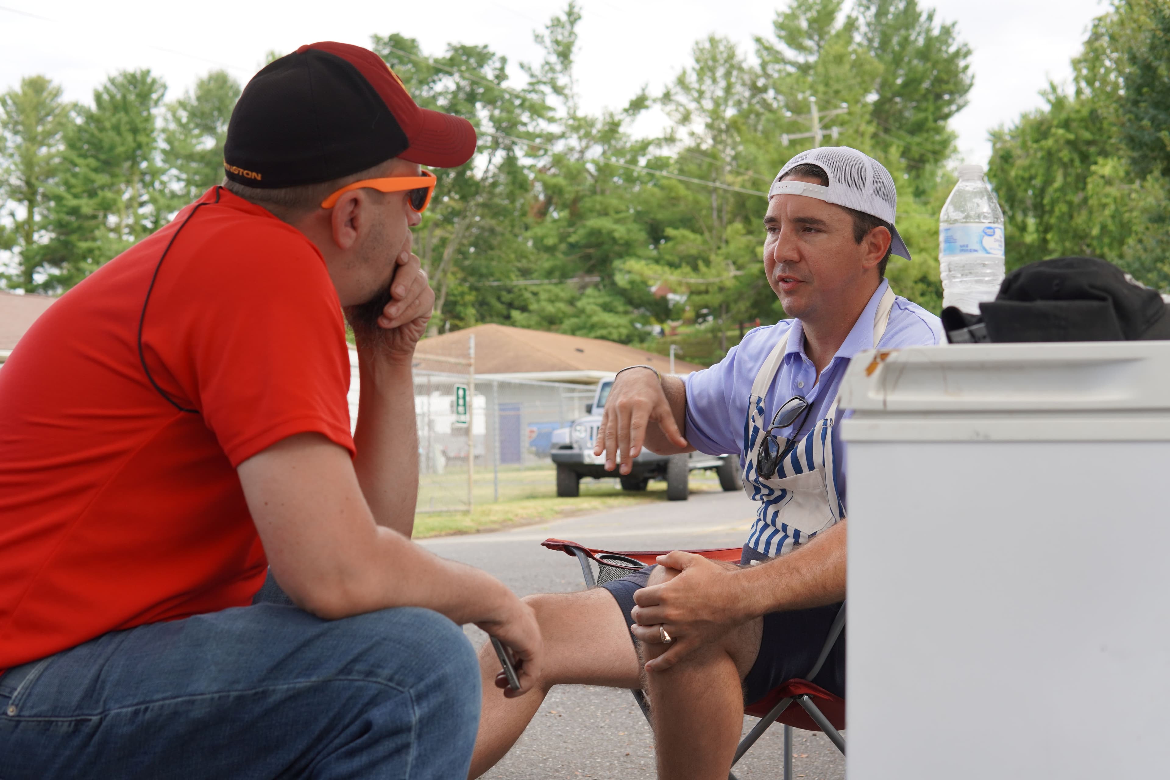 Two men in deep conversation at a Shenandoah Valley Teen Challenge community cookout, one listening intently