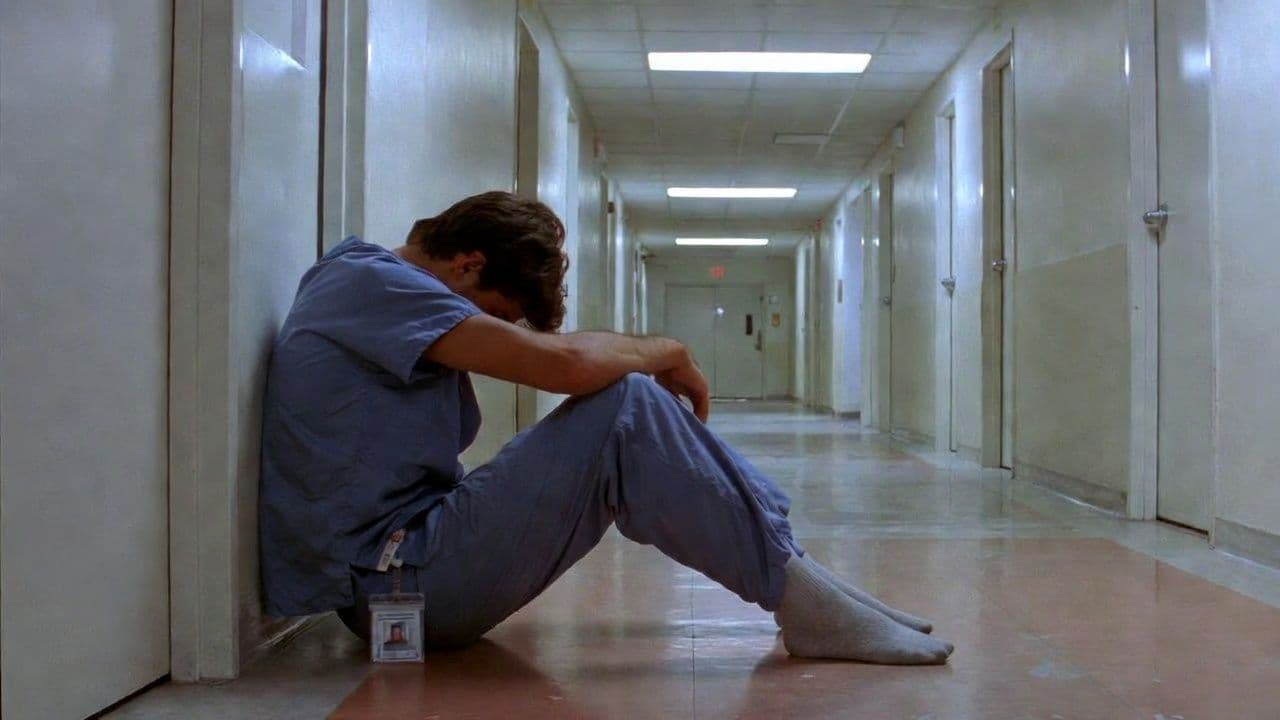 Exhausted healthcare worker sitting on a hospital hallway floor with head down, representing the toll of first responder trauma