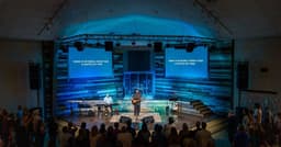 Josh Baldwin leading worship at Destiny Family Center with screens displaying "There is no sound louder than a captive set free"