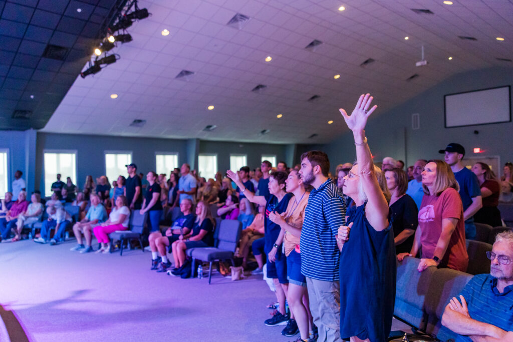 Community members at Open Door Church in Clearbrook, VA worshiping during a night of worship with Josh Baldwin, hands raised in praise.