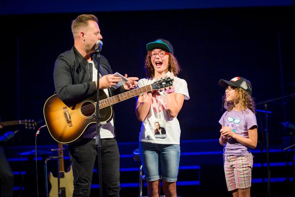 Matthew West engaging with two young attendees on stage during Teen Challenge Presents Matthew West in the Shenandoah Valley, spreading hope and joy through music.